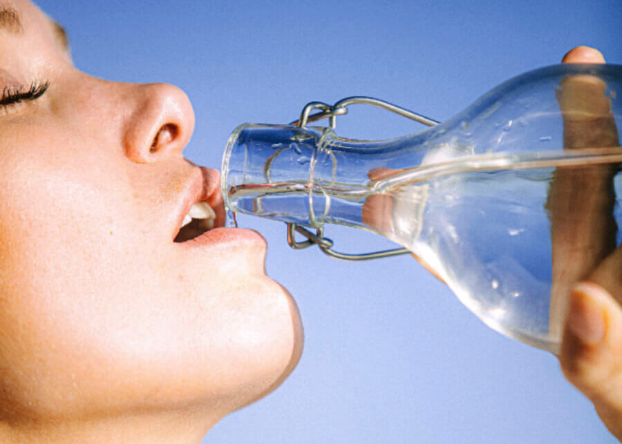 Photo d'un visage de femme buvant de l'eau à la bouteille