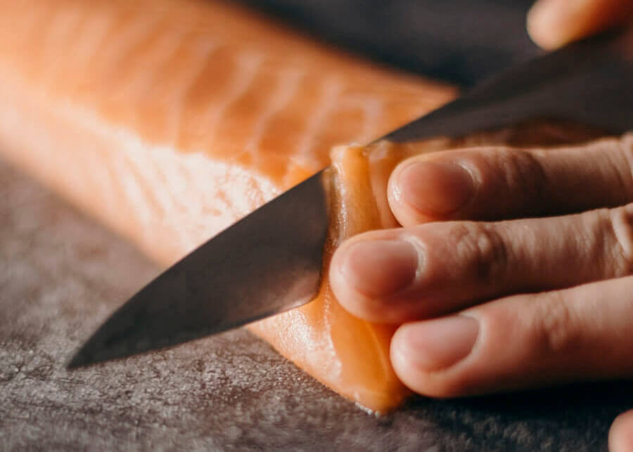 Photo de mains coupant un filet de saumon