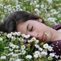 Photo d'une femme se reposant dans un champs de fleurs (troubles du sommeil insomnies réveils nocturnes)