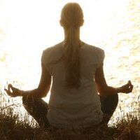 photo d'une femme se ressourçant en position de yoga (zen stress irritabilité)